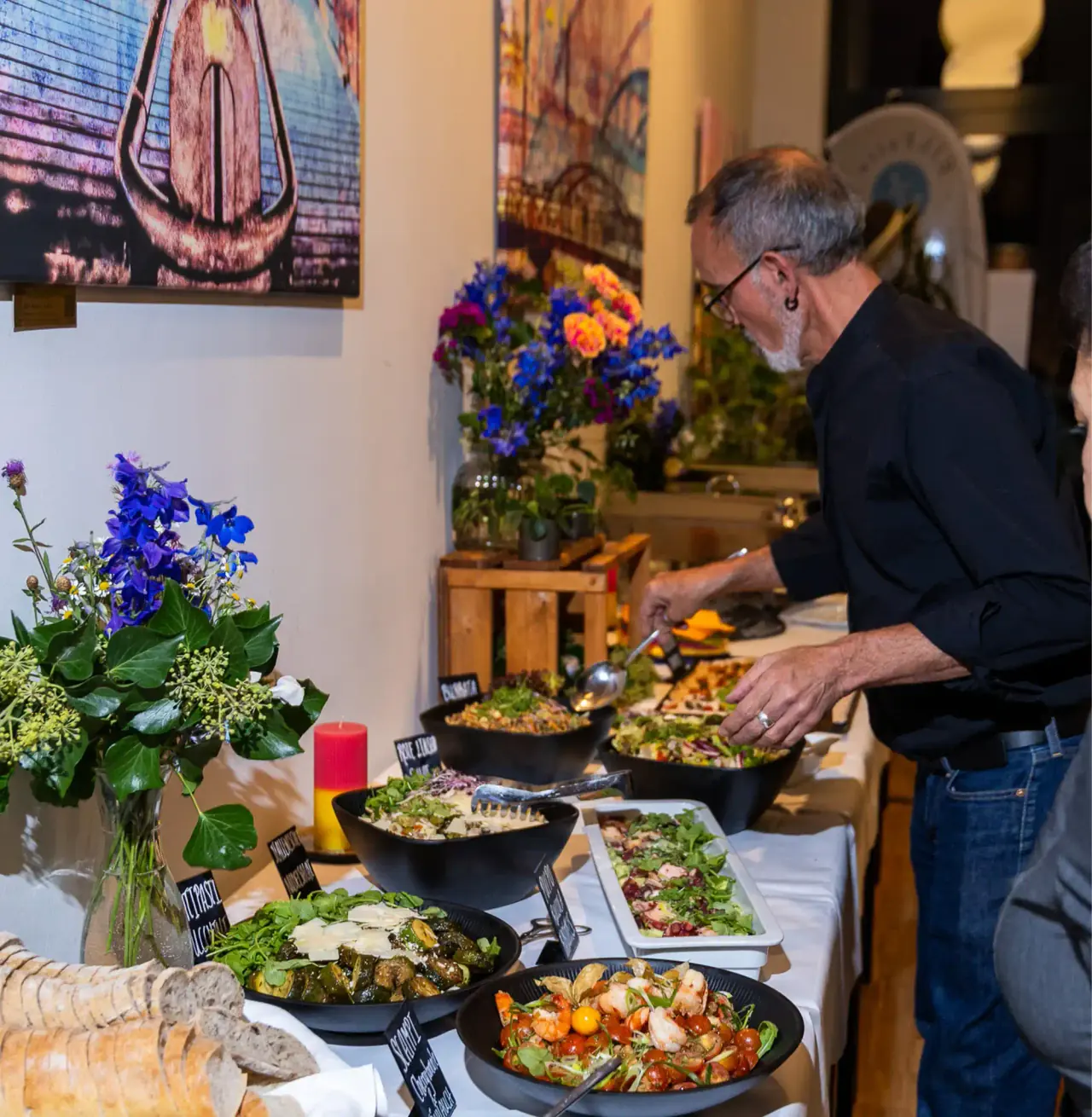 Mitarbeiter richtet ein Buffet mit Salaten und Blumendeko in der ElbFaire an